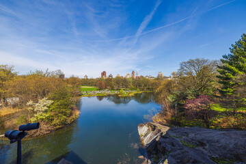 Beautiful view from Belvedere Castle overlooking the lake in Central Park, with people relaxing on the green lawns in early spring. NY.USA. - obrazy, fototapety, plakaty
