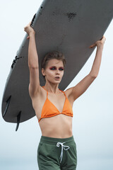Closeup of sensuality female surfer carrying white surfboard on her head during summer vacation