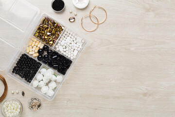 Tools and beads for making handmade jewelry on wooden background, top view