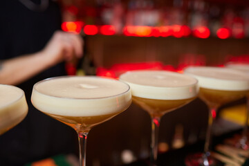 Bartender pours pink cocktail into martini glass with flair