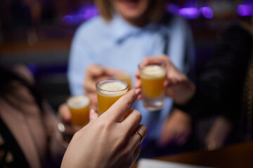 Group cheers with shot glasses of Paulaner hefeweizen wheat beer at fun event