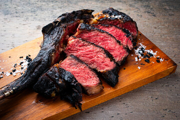 Traditional barbecue dry aged Kobe tomahawk steak with salt and black salt crystals served as...