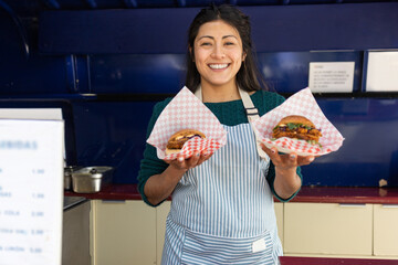 Smiling woman serving burgers at a food truck