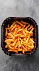 A top down image of an air fryer basket full of crinkle cut French fries