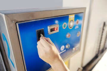 Close up of car wash service worker putting coin into machine.