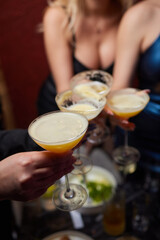 A woman holds a cocktail in her hand, with her fingers wrapped around the glass