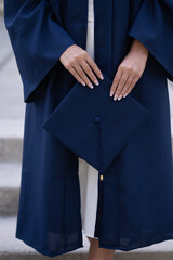 Young female hands holding navy graduation cap, verticle