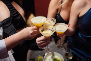 A woman holds a cocktail in her hand, with her fingers wrapped around the glass