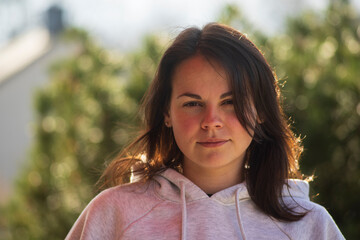 Portrait of a young brunette woman in a pink hoodie