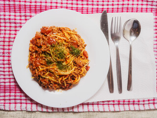 Spaghetti Bolognese serving on a white dish. Premium high quality meal with pasta, minced meat and tomato sauce. Top ingredients and herbs.