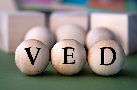 VED - acronym on wooden balls on the background of wooden large cubes