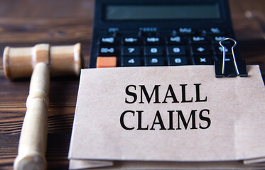 SMALL CLAIMS - words on light brown paper against the background of a calculator and a judge's gavel