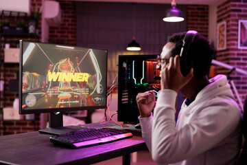 African american gamer excited about winning online multiplayer match against other players. Man...