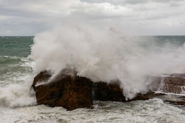 Waves hitting a sea rock with great force.