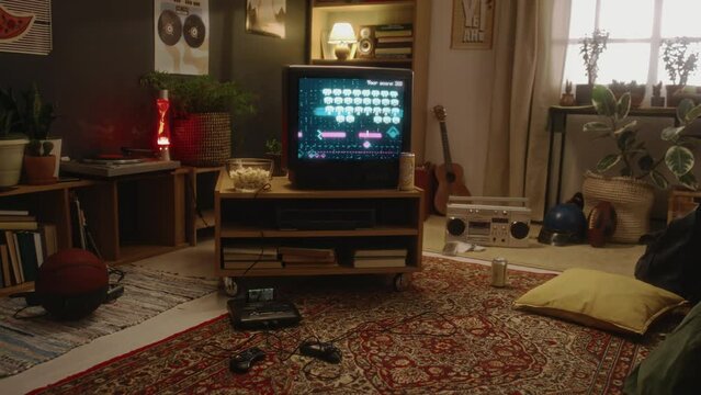 No people handheld footage of empty living room with old arcade shooter game on retro TV screen and consoles on carpeted floor, atmosphere of 90s