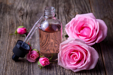 Obraz na płótnie Canvas Bottles of essential rose oil and flowers