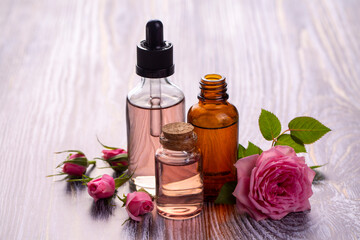 Obraz na płótnie Canvas Bottles of essential rose oil and flowers