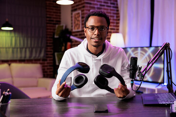 Portrait of technology reviewer recording headphones comparison episode using professional...