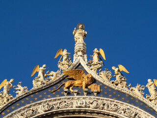 Obraz premium San Marcos statue above the Venice winged lion on the facade of St. Marks Basilica, Venice
