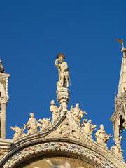 Fototapeta na wymiar Statue of a Saint atop the facade of San Marco Basilica, Venice