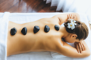 Hot stone massage at spa salon in luxury resort with day light serenity ambient, blissful woman...