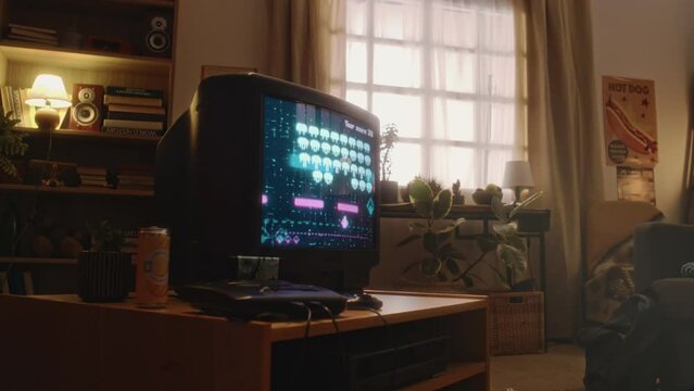No people footage of old space shooter game picturing battle with swarms of aliens on tube TV screen in retro-styled living room in 90s