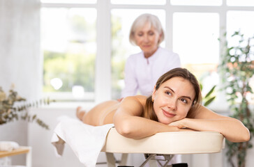 Vague mature female masseuse doing massage treat lower back pain, arm pain, stress for woman tired...