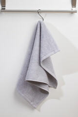 a terry towel hangs on a metal bracket attached to the wall
