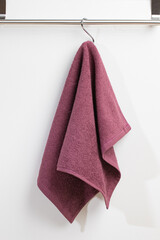 a terry towel hangs on a metal bracket attached to the wall