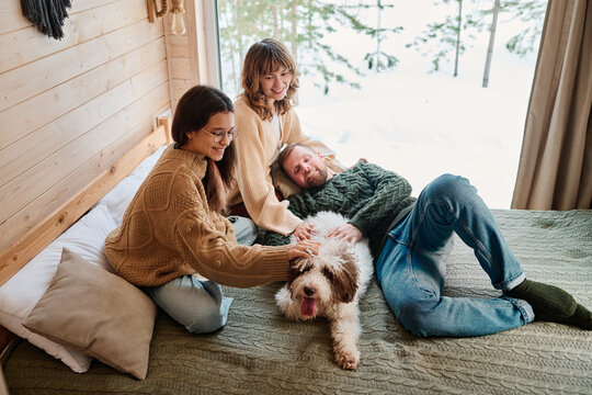 High angle view shot of modern family of three with lagotto romagnolo dog enjoying spending cold winter day at home