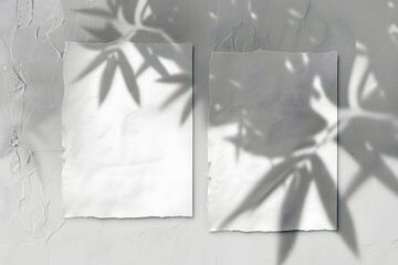2 vertical sheets of textured white paper on soft gray table background. Mockup overlay with the plant shadows. Natural light casts shadows from an exotic plant. Horizontal orientation - obrazy, fototapety, plakaty