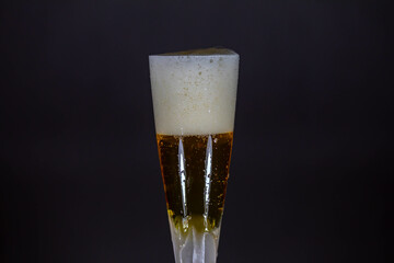 Cold beer dripping foam into glass