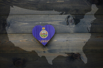 wooden heart with national flag of kansas state near united states of america map on the wooden...