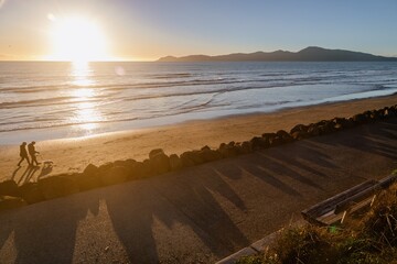Poeple walking a god on the beach front of Raumati. In the background is Kapiti Island....