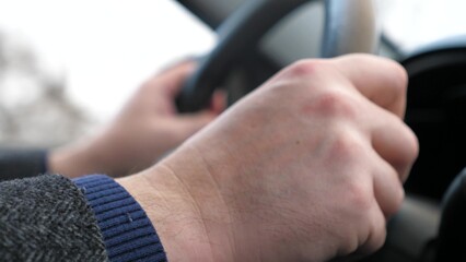 Man driving car transportation hands holding steering wheel closeup. Male arm riding automobile transport enjoy freedom speed drive road trip travel exploration at countryside highway