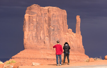 West Mitten, Monument Valley, illuminated by setting sun with very dark sky in background. Man and...