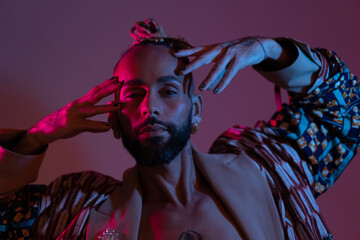 Neon light studio close-up portrait handsome black gay man looking camera. Seductive sexy man wear...