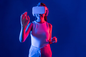 Smart female standing with surrounded by cyberpunk neon light wear VR headset connecting metaverse,...