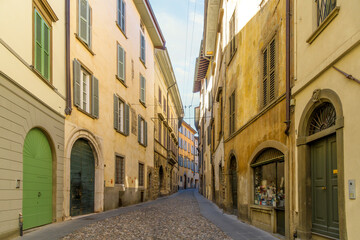 A picturesque narrow alley leading in the historic medieval old town walled Città Alta district, the historic upper district of the city of Bergamo, Italy, in the Lombardy region.	