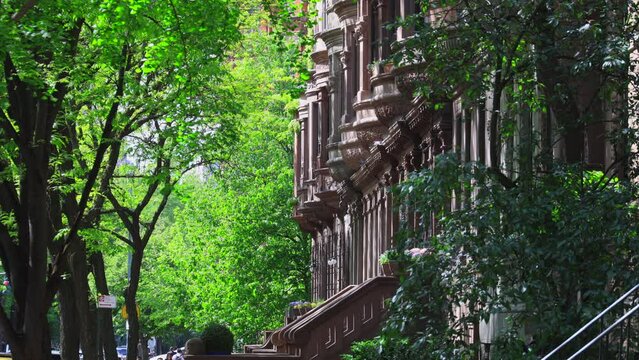 NEW YORK, NEW YORK, USA - MAY 8 2023: Rows of fresh green trees grow along row of Apartment buildings in Central Park West Historic District during spring season at Upper West Side Manhattan in New Yo