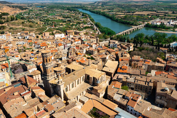 Naklejka premium Scenic aerial view of medieval Roman Catholic Cathedral of Saint Mary surrounded by residential buildings with terracotta tiled roofs in historical center of Tudela on sunny spring day, Spain
