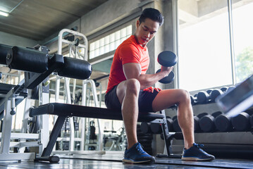 Attractive young man Lifting dumbbells in the gym. Exercise concept.