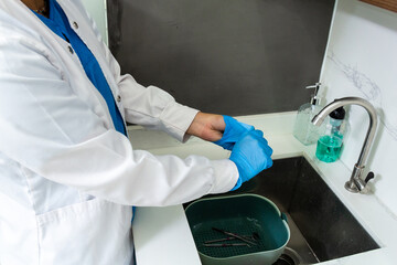 Female dental assistant or nurse taking off clinical latex gloves. Getting ready for washing hands...