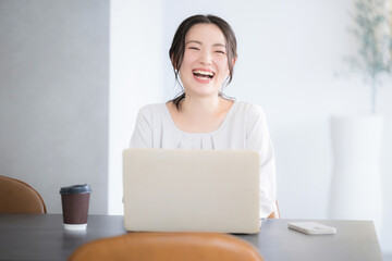パソコンの前で大笑いする幸せな笑顔のかわいい女性 成功などのイメージ