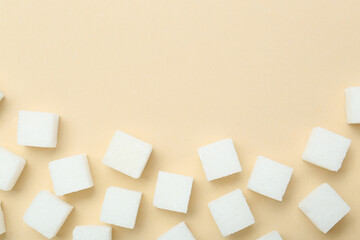 White sugar cubes on beige background, top view. Space for text