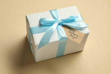 Card with phrase Happy Father's Day and gift box on beige background