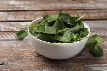 Fresh spinach leaves in bowl on wooden rustic table, closeup