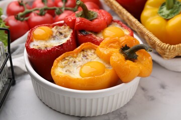 Delicious stuffed peppers with eggs in bowl on white marble table