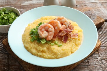 Plate with fresh tasty shrimps, bacon, grits and green onion on wooden table