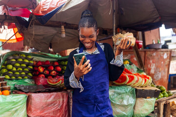 Happy Female Fruit Vendor Excited with Cash and Mobile Phone - Surprise Expression